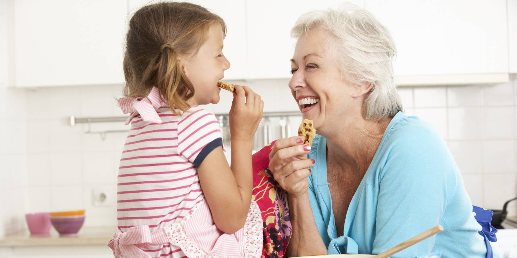 Petite fille et grand-maman, avec chacune un biscuit à la main.